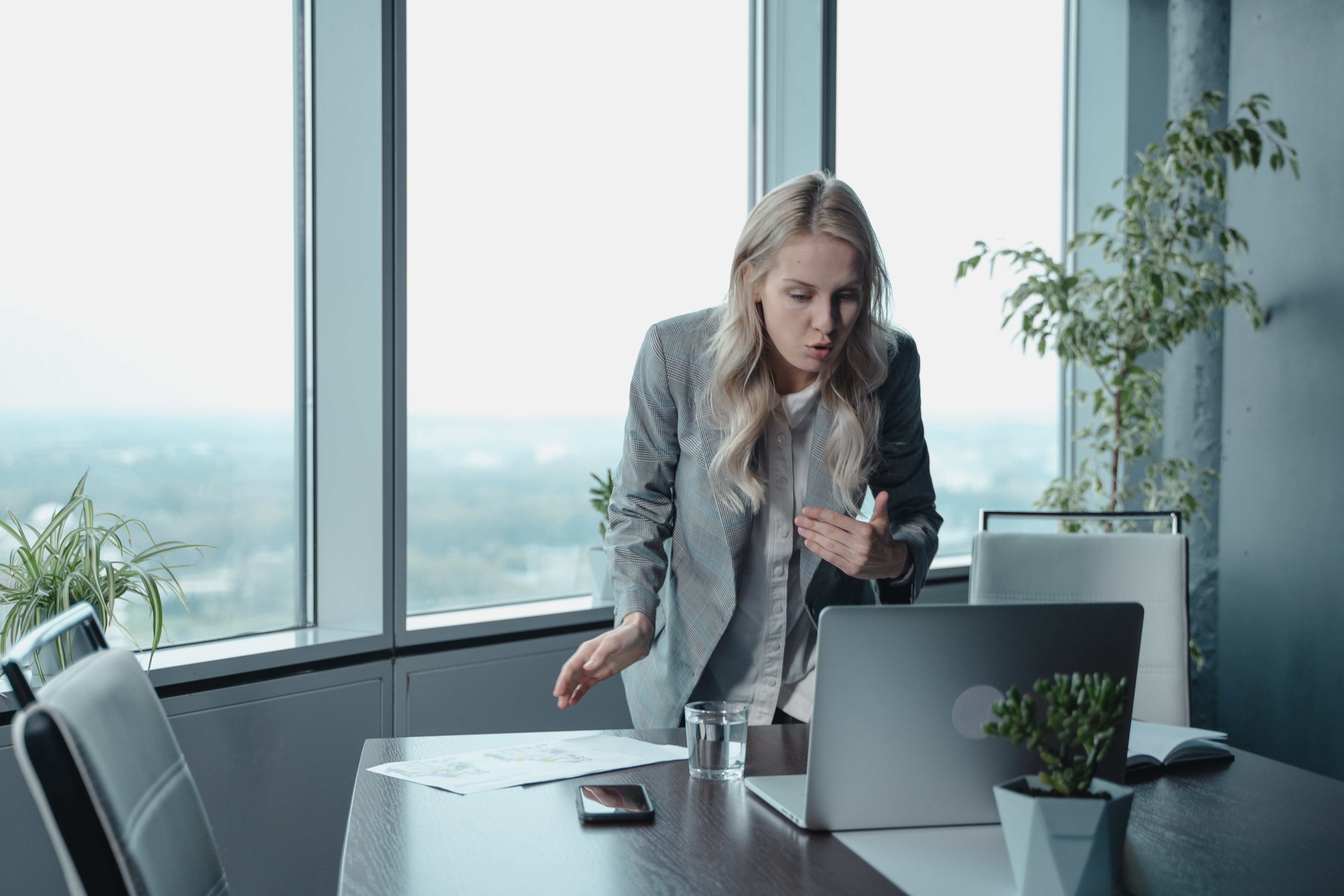 A person looking frustrated at their computer in front of windows