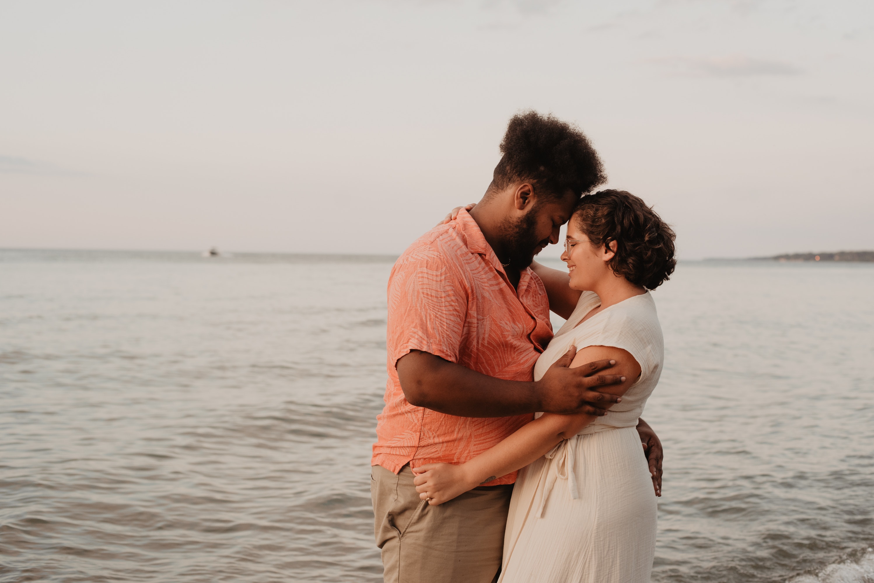 A couple holding eachother in front of a body of water