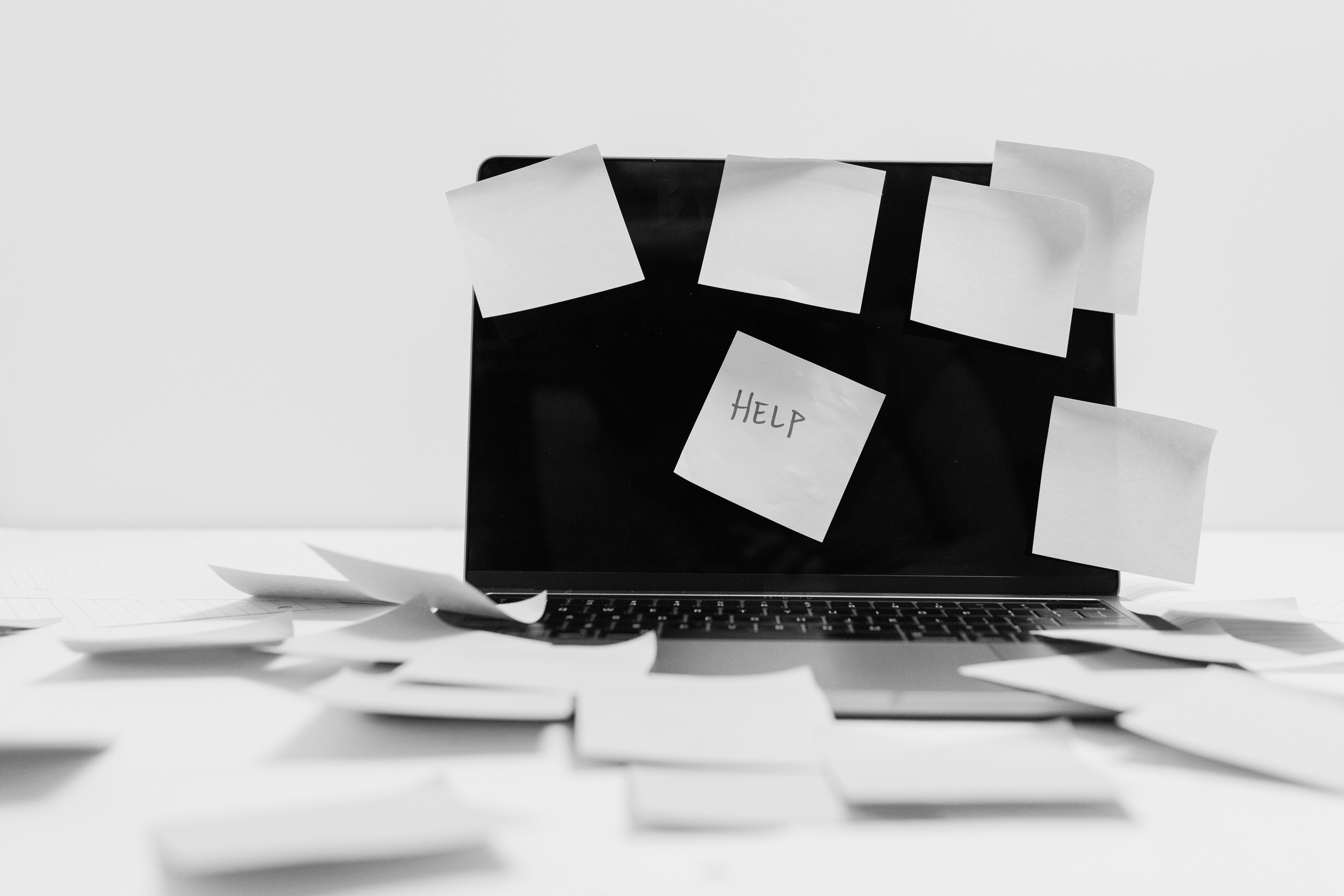 A laptop with sticky notes all over it, and one in the middle that says Help