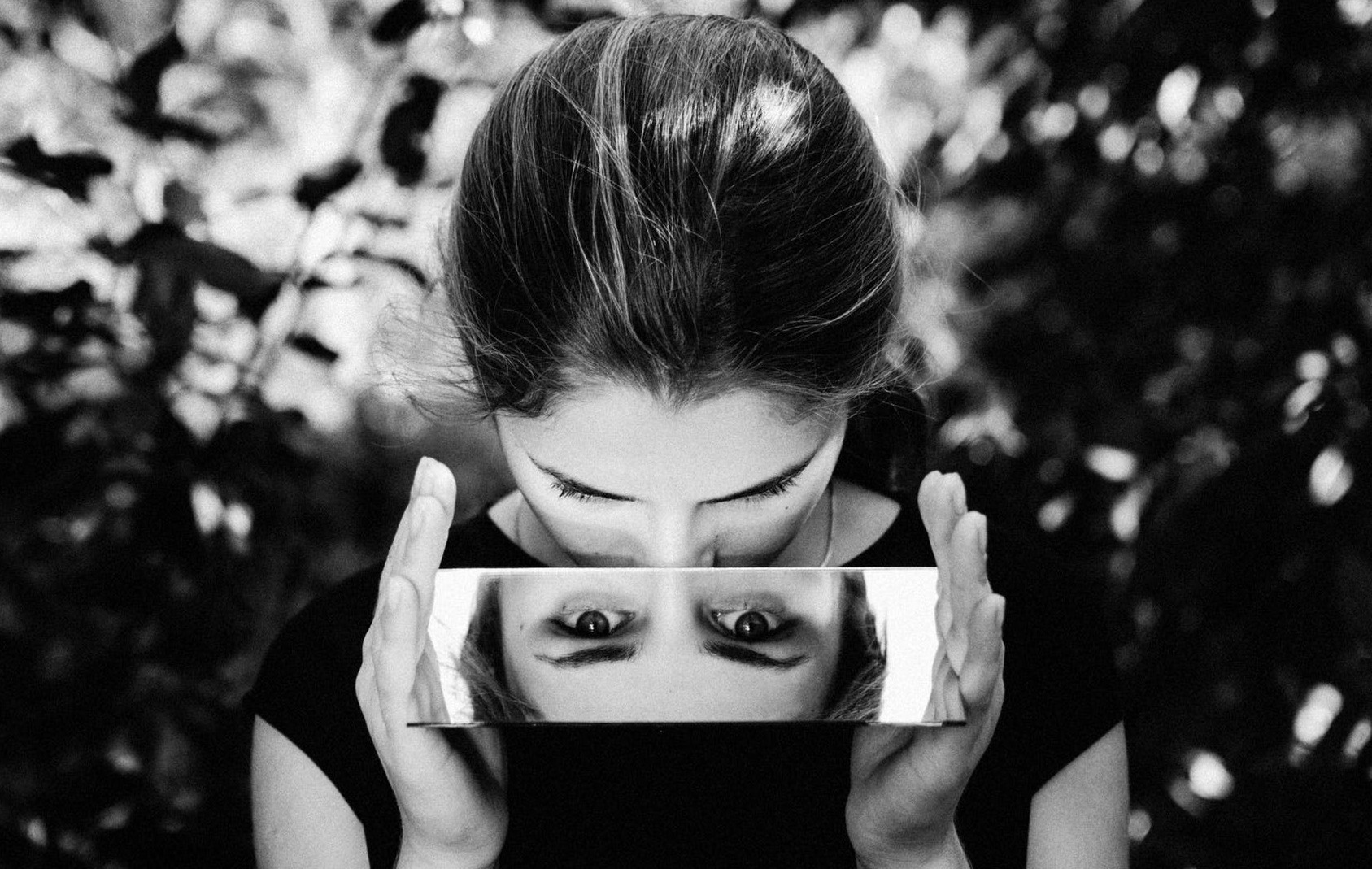 A person looking into a mirror in black and white